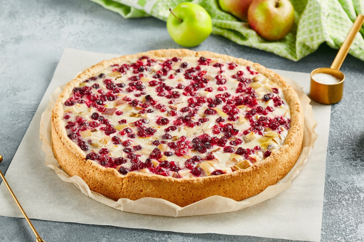 Ein ganzer Apfel-Cranberry-Kuchen auf einem StÃ¼ck Backpapier.