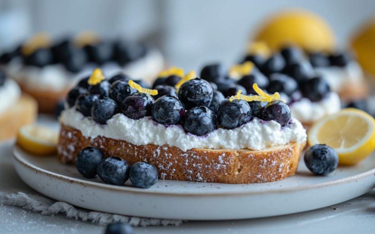 Ein Blaubeer-Ricotta-Röstbrot mit Zitronenzesten auf einem Teller.