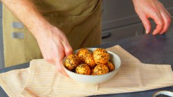 Ein Koch richtet frittierte Parmesanbälle in einer Schale an.