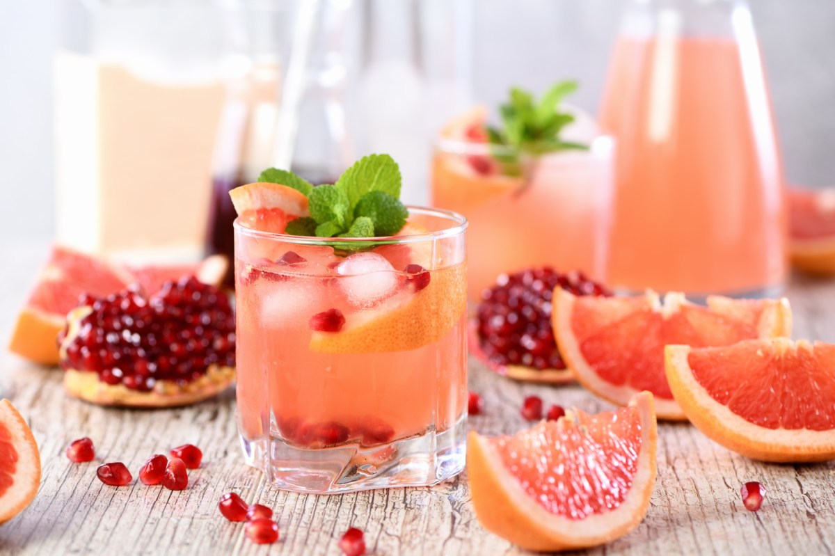 Mehere GlÃ¤ser und eine Karaffe Grapefruit-Granatapfel-Mocktail, daneben liegen die Zutaten.