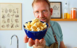 Ein Koch hält eine Schüssel Parmesan-Popcorn in die Kamera.