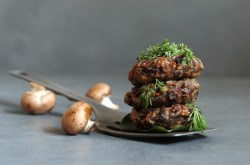 Stapel mit veganen Champignon-Buletten, Champignons daneben