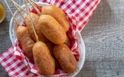 Mehrere vegane Corn Dogs in einem ovalen Korb. In der Draufsicht.