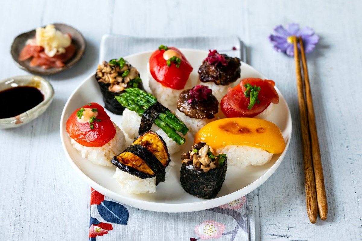 Farbenfrohes, veganes Sushi auf einem weiÃŸen Teller. Daneben liegen EssstÃ¤bchen.