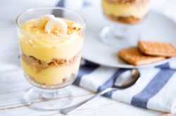 Ein Dessertglas mit Bananen-Buttercreme-Dessert. Im Hintergrund sieht man verschwommen ein weiteres Glas.