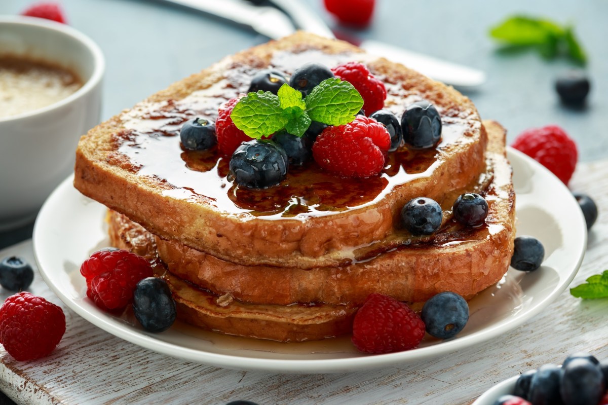 Ein Teller French Toasts aus der Heißluftfritteuse mit Beeren und Ahornsirup, Nahaufnahme.