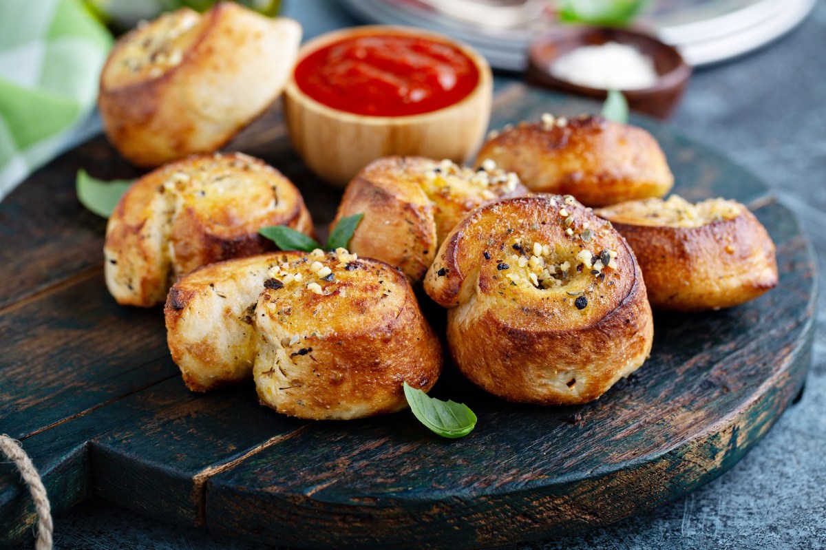 Knoblauchschnecken auf einm dunklen Holzbrett. serviert mit Tomatendip.