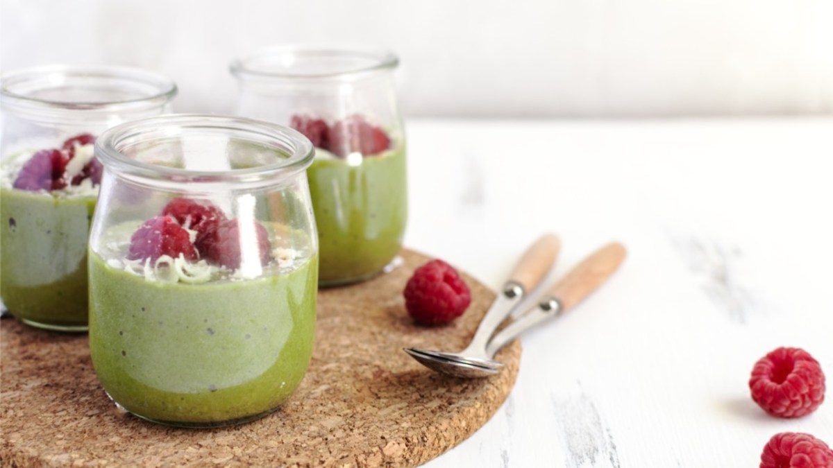 Drei Gläser Matcha-Pudding mit Himbeeren.